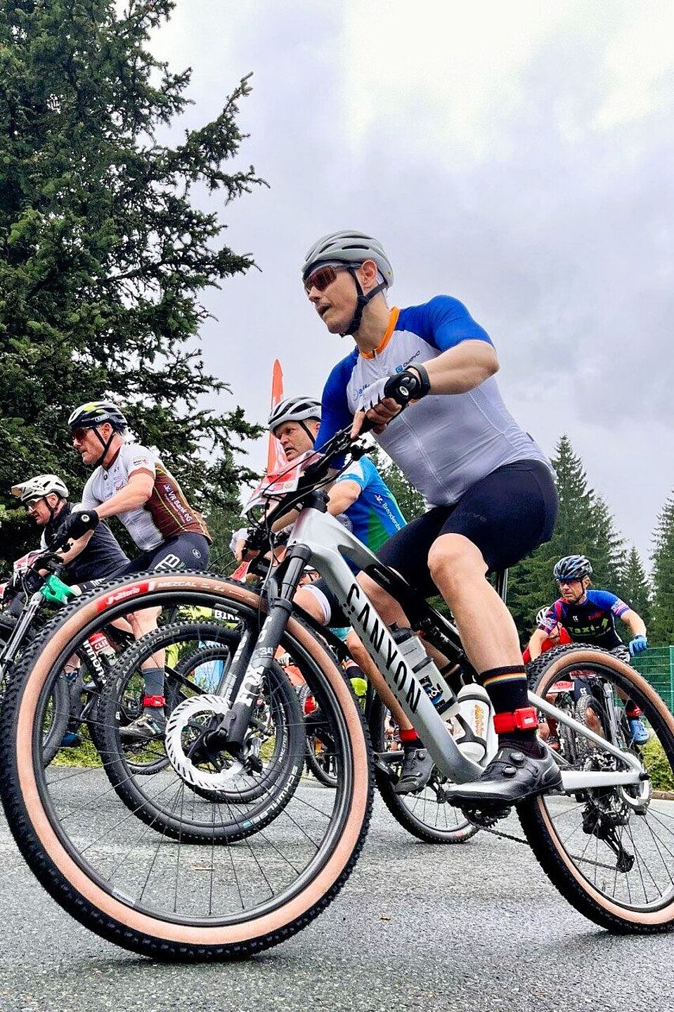 Canyon Seitenaufnahme eines Mountainbikers, der sich außen im Fahrerfeld eines MTB-Rennens befindet.