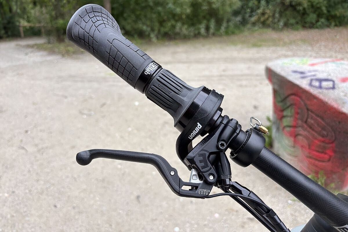 Großaufnahme eines rechten Lenkerendes mit Griffen von SQlab, Bremsen von Magura und Schaltdrehgriff von Pinion. 