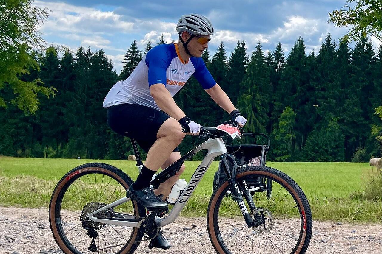 Ein Mountainbiker in der Seitenansicht fährt einen Schotterweg hinauf. 
